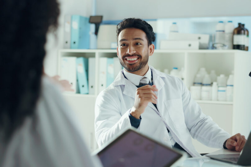 Man, scientist and smile in lab with colleague for microbiology study, report or discovery discussion. Team, microscope and technology for medical research, pharmaceutical development and solution.